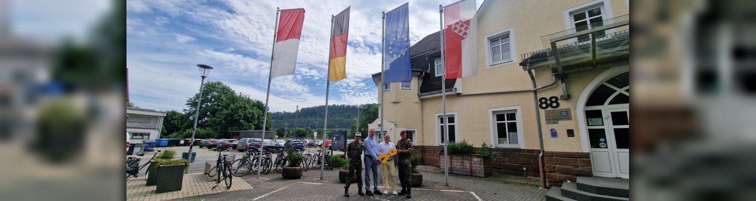 v.l.n.r. Oberst Andreas Döring, Vorsitzender der Gemeindevertre-tung Prof. Dr. Dr. Herzberg und Bürgermeister Dr. Jens Ried (halten die Gelbe Schleife) und Hauptmann Martin Würz vor den gehissten Flaggen auf dem Rathausvorplatz